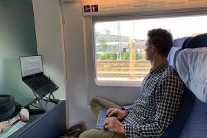 Mann arbeitet während der Zugfahrt am Laptop