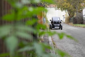 Das Elektrische Leichtfahrzeug Renault Twizy hinter unscharfen Blättern.