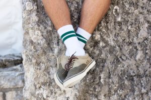 Verschränkte Füße mit weißen Socken mit grünen Streifen
